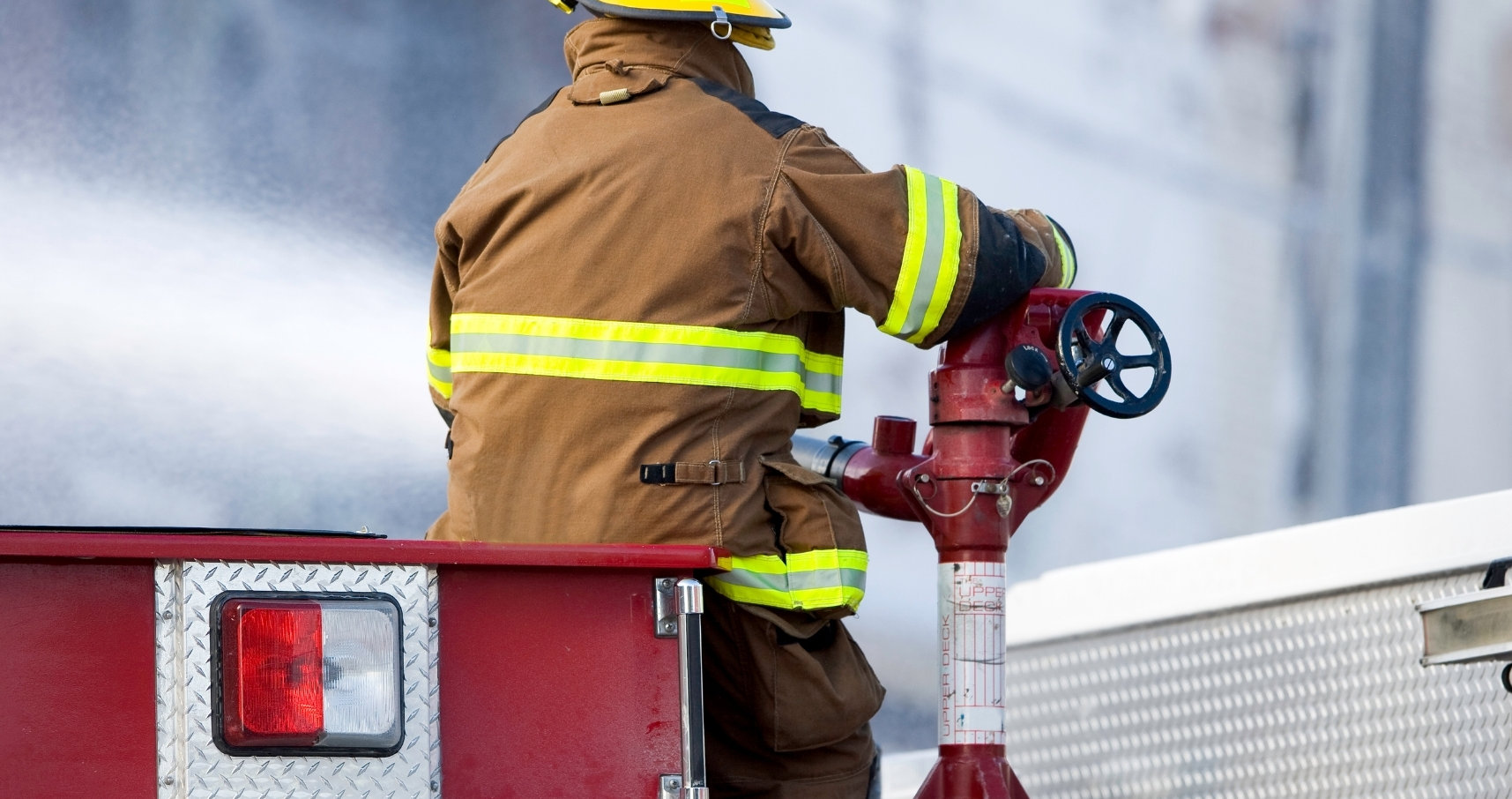 A firefighter on a truck spraying out a fire